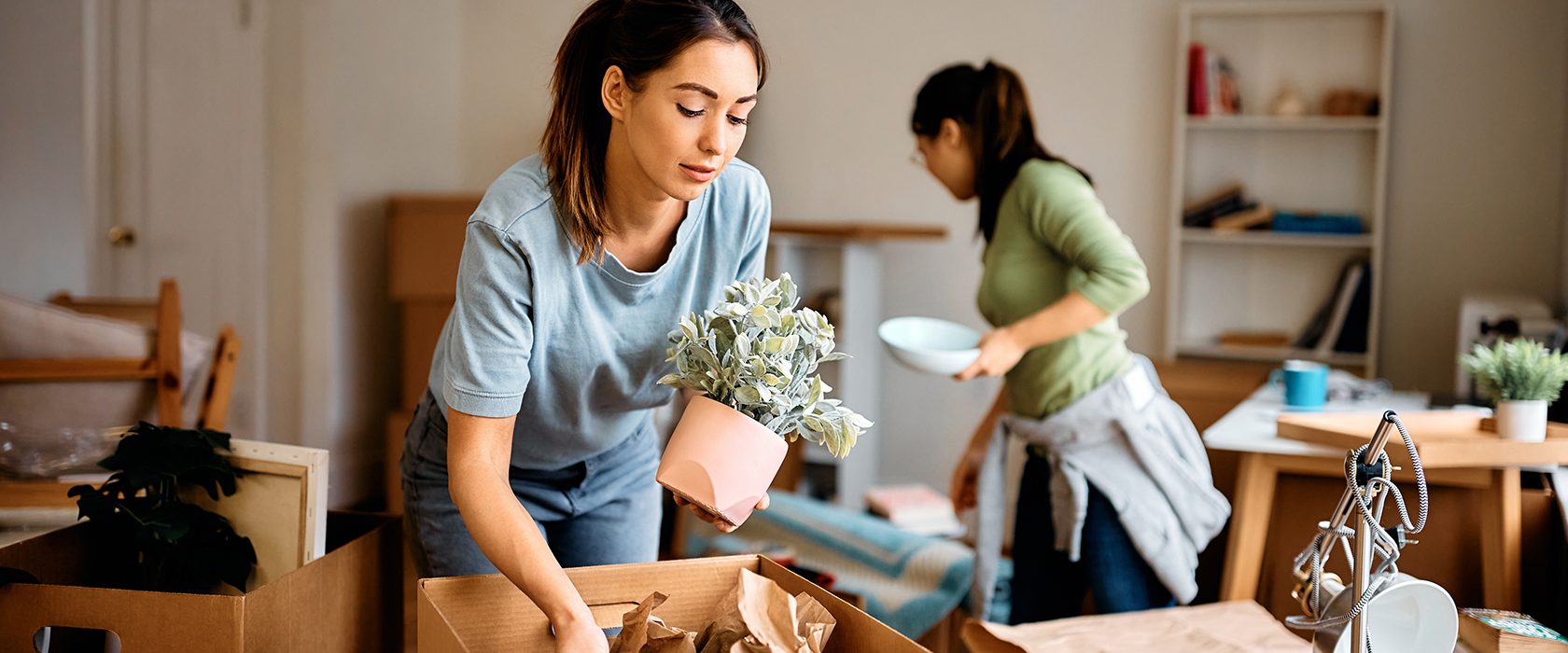 Zwei junge Frauen beim Umzugskartons auspacken.